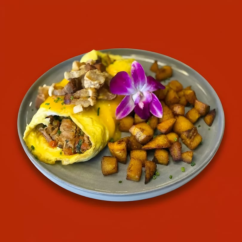 Omelet with meat filling, topped with crispy pork rinds, a purple orchid, and roasted potatoes.